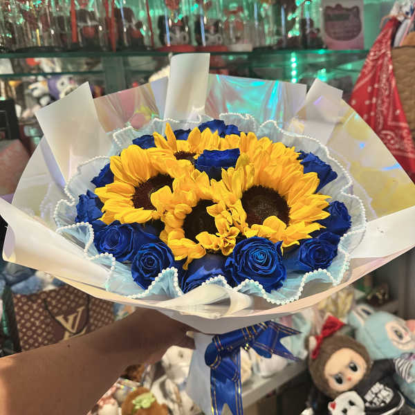 Bouquet of yellow sunflowers and blue roses wrapped in white paper