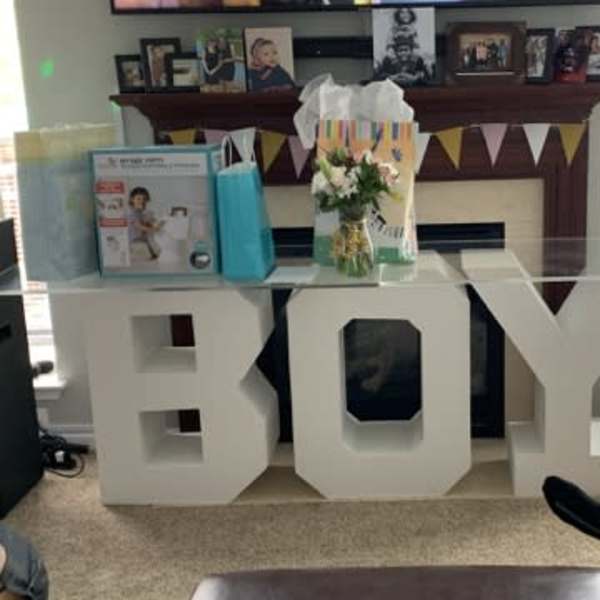 Small flower arrangement beside a large white "BOY" decoration