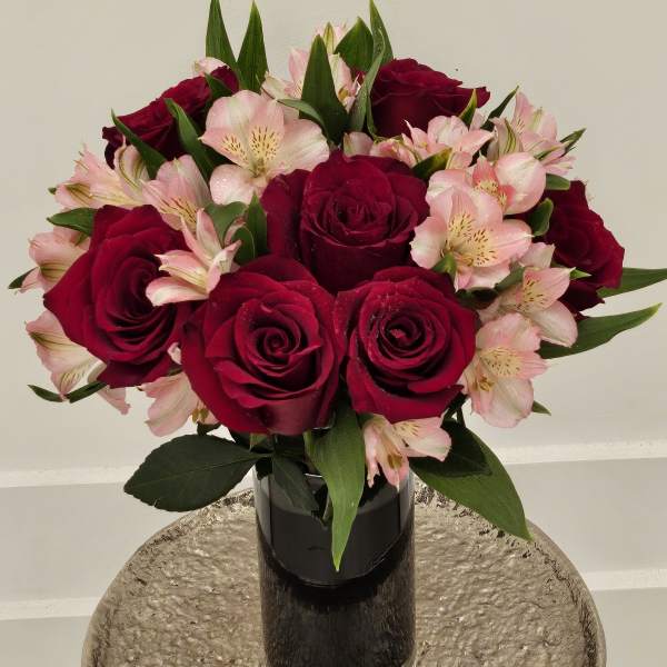 Bouquet of red roses and pink alstroemeria in a black vase