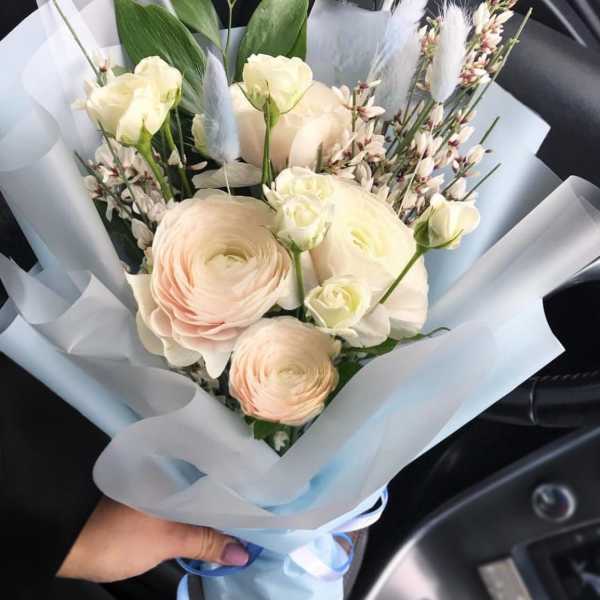 Bouquet of pale cream and blush flowers wrapped in light blue paper