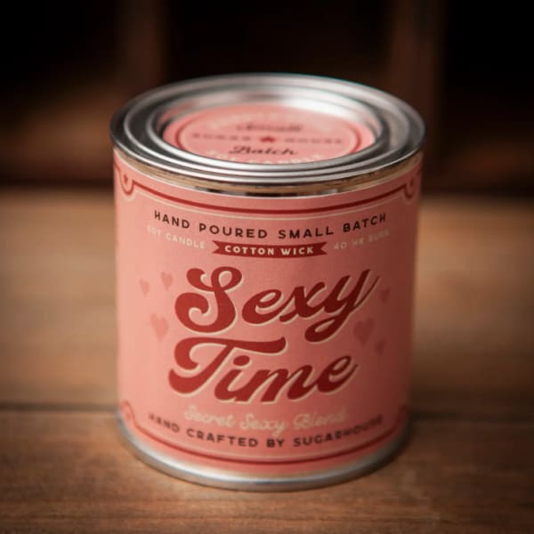 Pink candle in a metal tin labeled "Sexy Time"