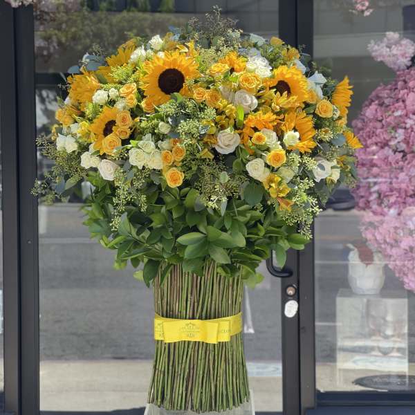Large bouquet of sunflowers and white roses with a yellow ribbon