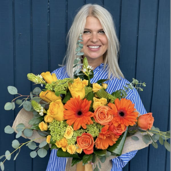 Woman holding a bouquet of orange and yellow flowers