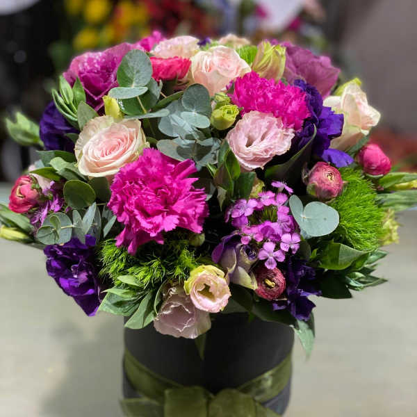 Bouquet of pink, purple, and white flowers in a black box with ribbon