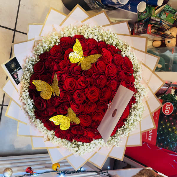 Heart-shaped bouquet of red roses with white baby's breath and gold butterfly accents