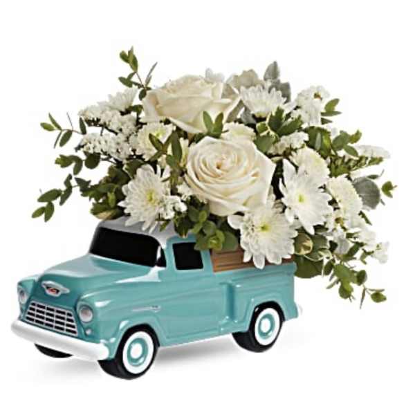 White roses and daisies arranged in a turquoise toy truck