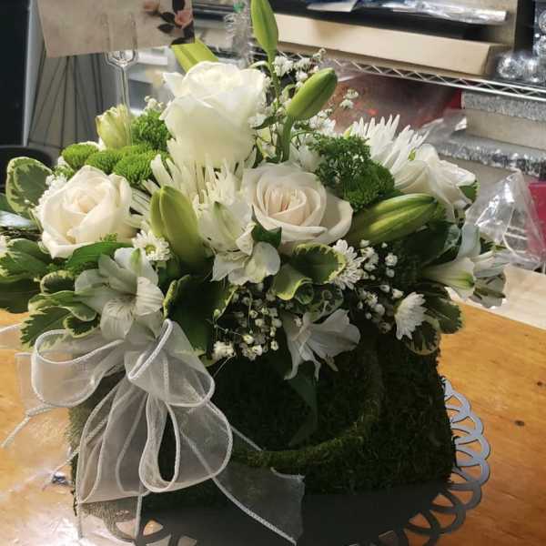 White roses and lilies arranged in a round box with a white ribbon