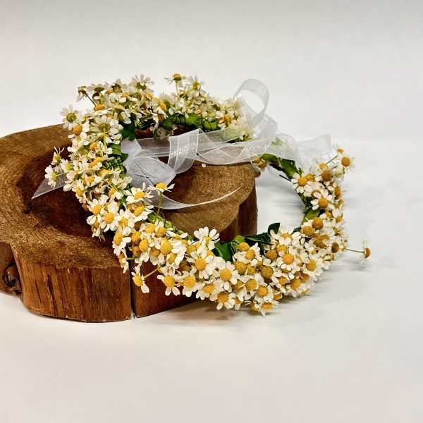 Daisy flower crown with white ribbon on a wooden stand