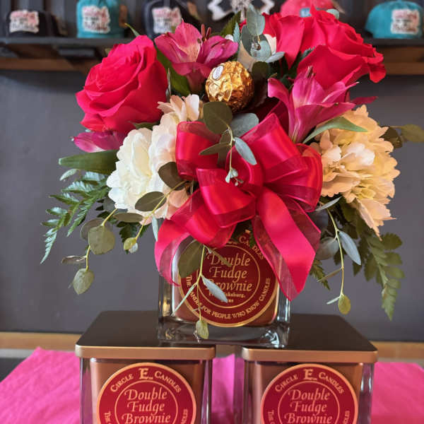 Bouquet of pink roses and mixed blooms with a red ribbon, arranged over candles