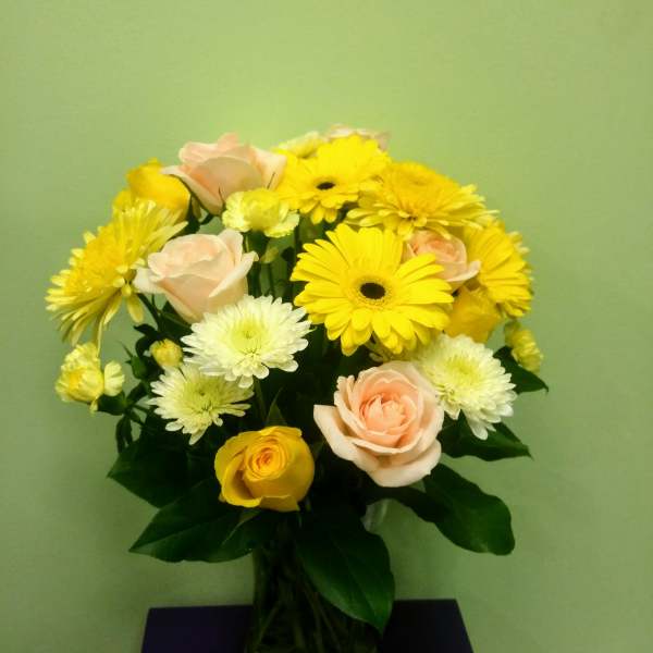 Bouquet of yellow and pale pink flowers in a glass vase