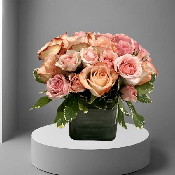 Pink and peach roses arranged in a dark green vase