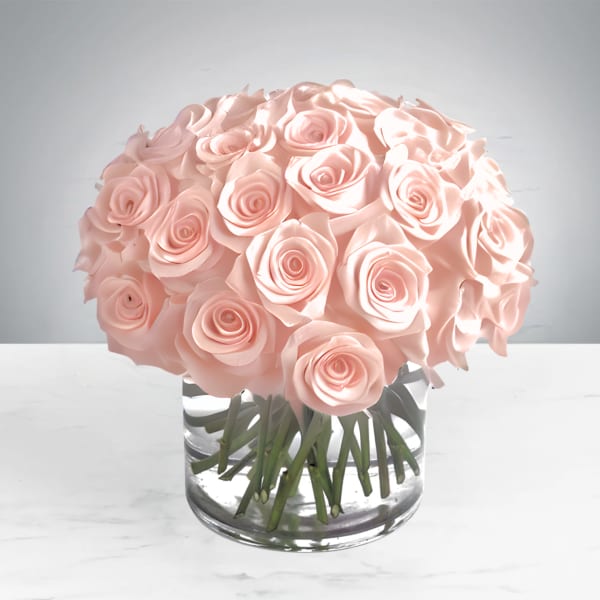 A round bouquet of pale pink roses in a clear glass vase.