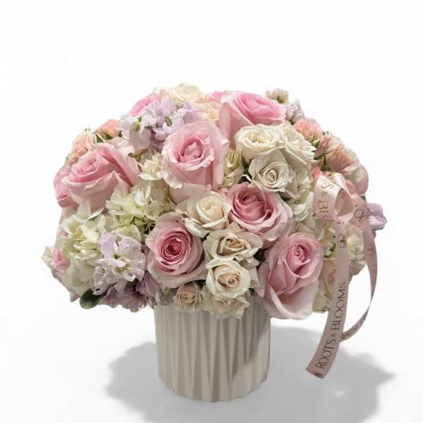 Pink and white rose bouquet in a ribbed cream vase