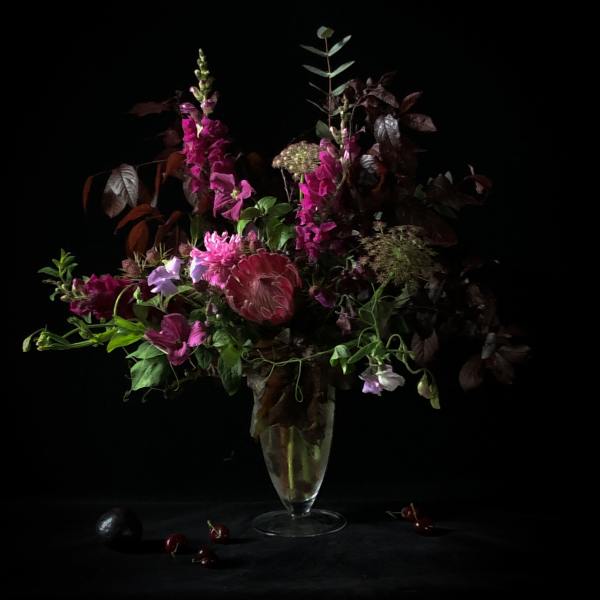 Tall magenta and purple floral arrangement in a clear vase