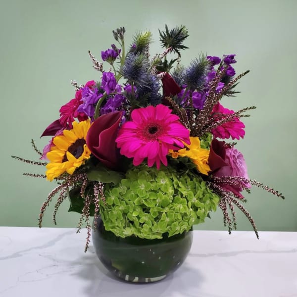 Bright mixed flower arrangement in a dark glass vase