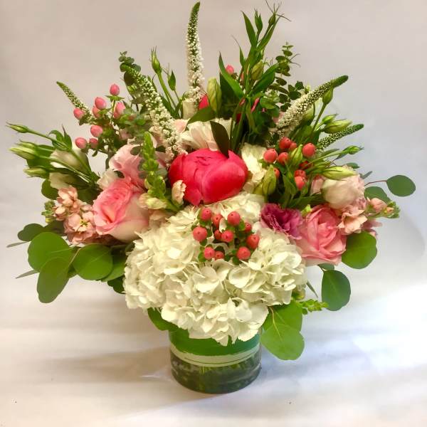 Pink and white flower arrangement with hydrangeas and roses in a clear glass cylinder vase