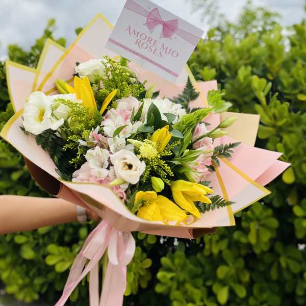 Bouquet of white, pink, and yellow flowers wrapped in pastel paper