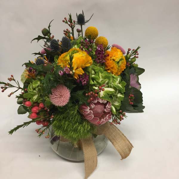 Mixed bouquet in a glass vase with yellow, pink, and purple blooms