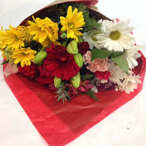 Bouquet of yellow, red, and white daisies wrapped in red paper