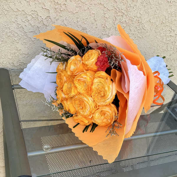 Bouquet of orange and yellow roses wrapped in pastel paper