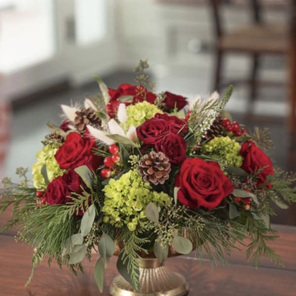 Red roses and green hydrangeas arranged in a gold vase