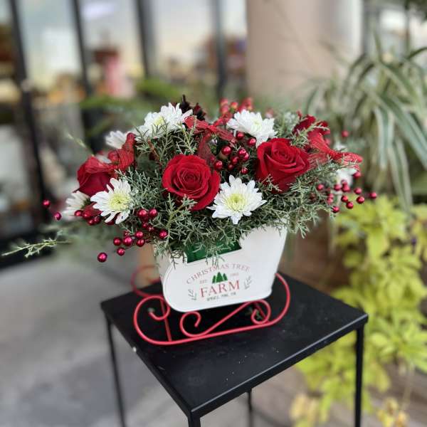 Red roses and white daisies in a white holiday container