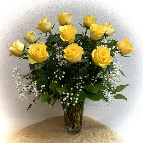 Yellow roses in a clear glass vase with white baby's breath