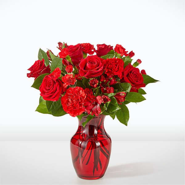 Red roses and carnations in a red glass vase
