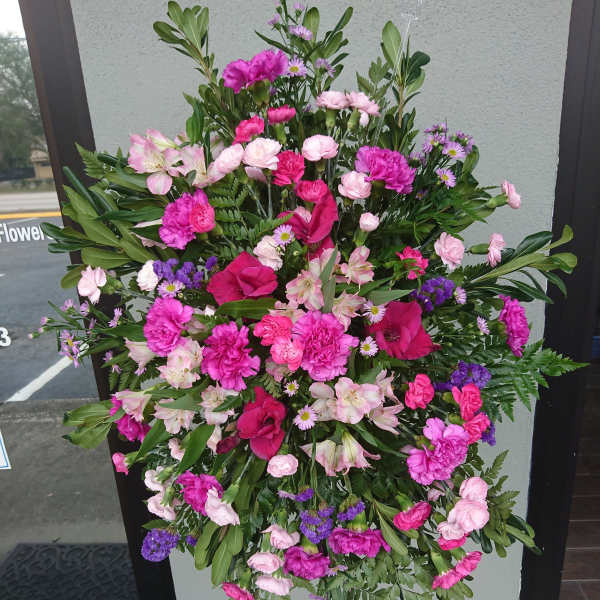 Large pink and purple funeral spray on a stand