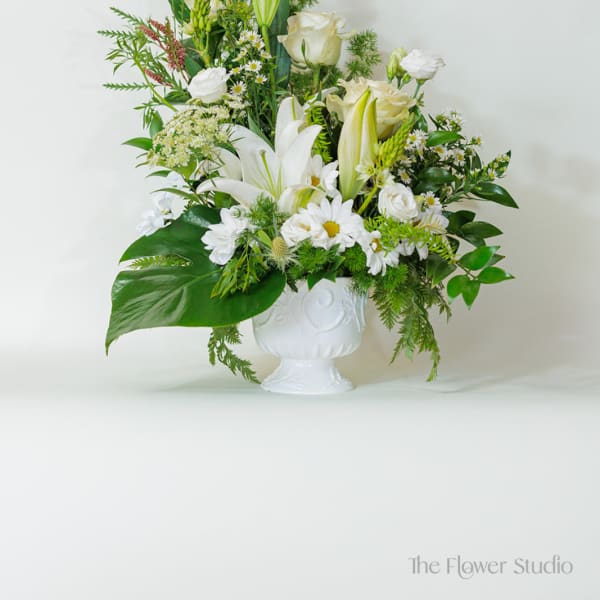 White floral arrangement in a white pedestal vase