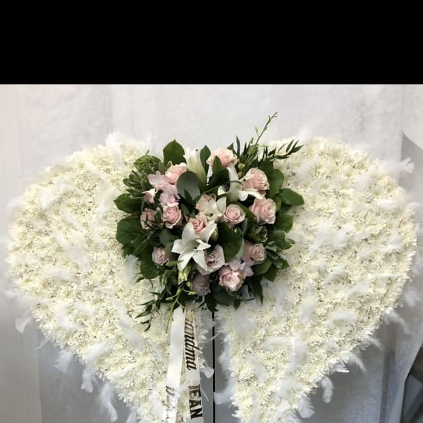 Heart-shaped white funeral spray with pink roses and lilies