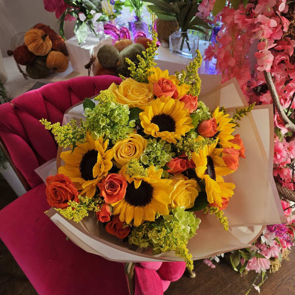 Bouquet of sunflowers, yellow roses, and orange roses wrapped in paper