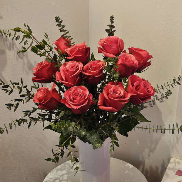 Bouquet of red roses in a white vase with eucalyptus