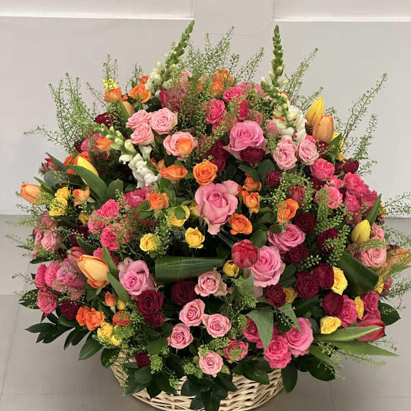 Large basket arrangement of pink, red, orange, and yellow roses