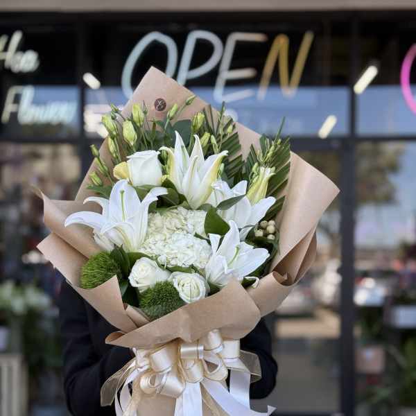White lily and rose bouquet wrapped in kraft paper with ribbon