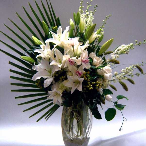 White lilies and orchids arranged in a clear glass vase