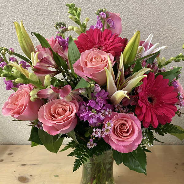 Pink roses and hot pink gerbera daisies in a clear glass vase