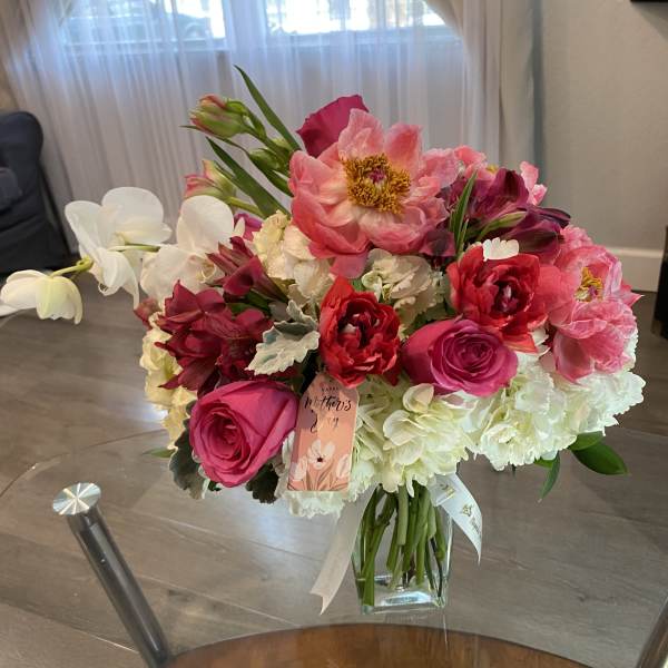 Pink and white mixed bouquet in a glass vase with a Mother's Day tag