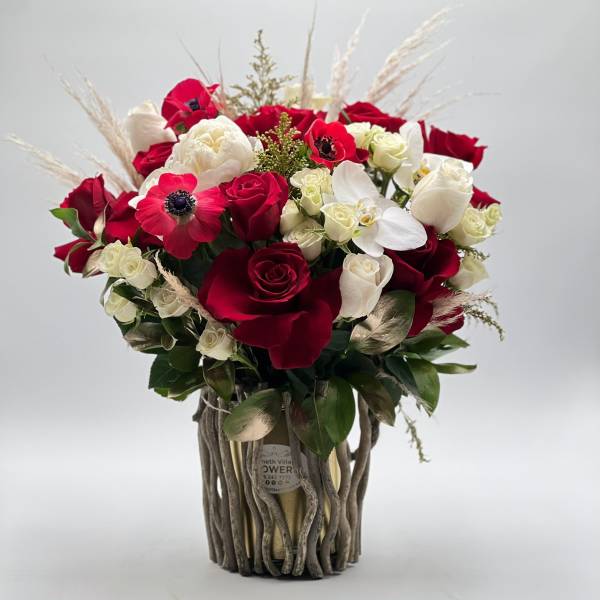 Red and white rose bouquet in a rustic twig vase
