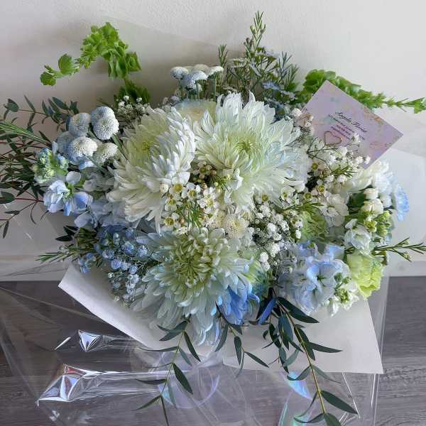 Bouquet of white and pale blue flowers wrapped in white paper