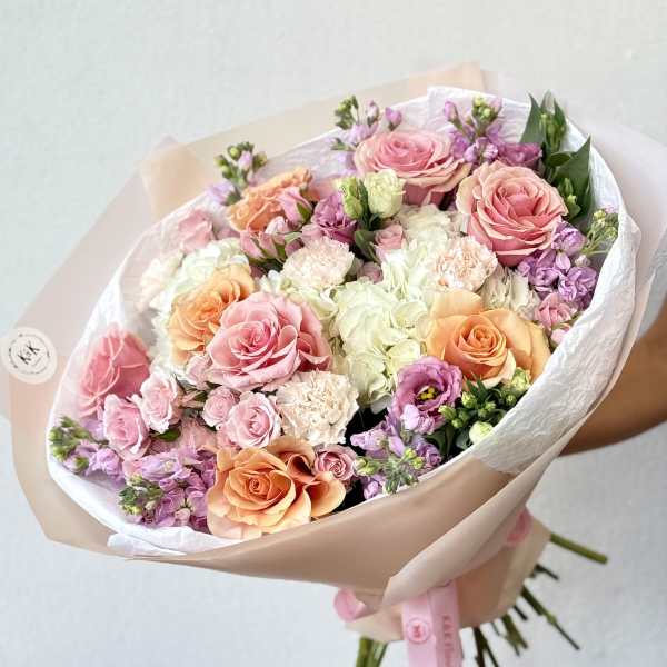 Hand-tied bouquet of pink, peach, and white roses with pastel filler flowers