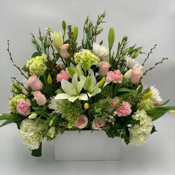 Large floral arrangement with pink roses, white lilies, and pale green hydrangeas in a white box