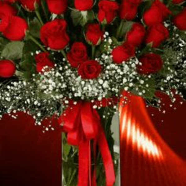 Bouquet of red roses in a clear glass vase with a red ribbon