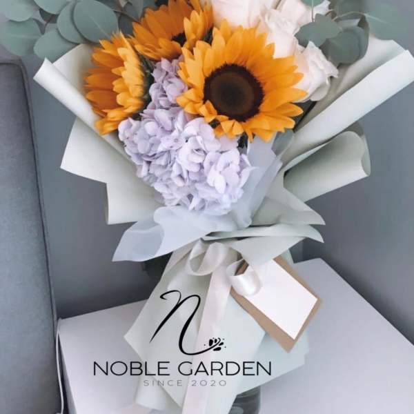 Bouquet of sunflowers, white roses, and lavender hydrangea with eucalyptus wrap