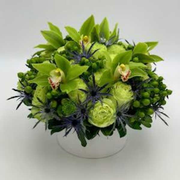Green floral arrangement in a round white vase