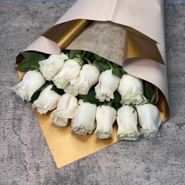 Bouquet of white roses wrapped in white and gold paper