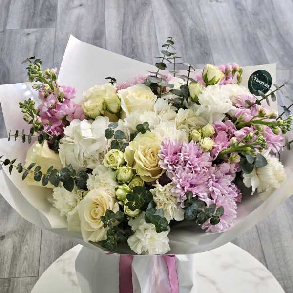 Bouquet of white and pale pink flowers wrapped in white paper