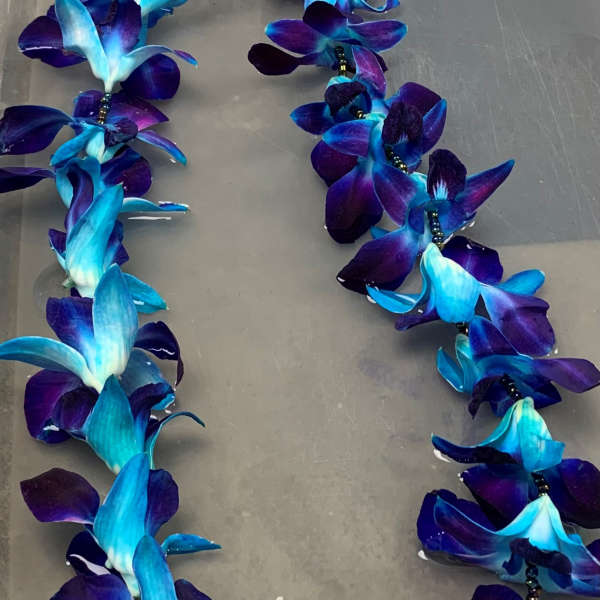 Blue and purple orchid lei on a gray surface