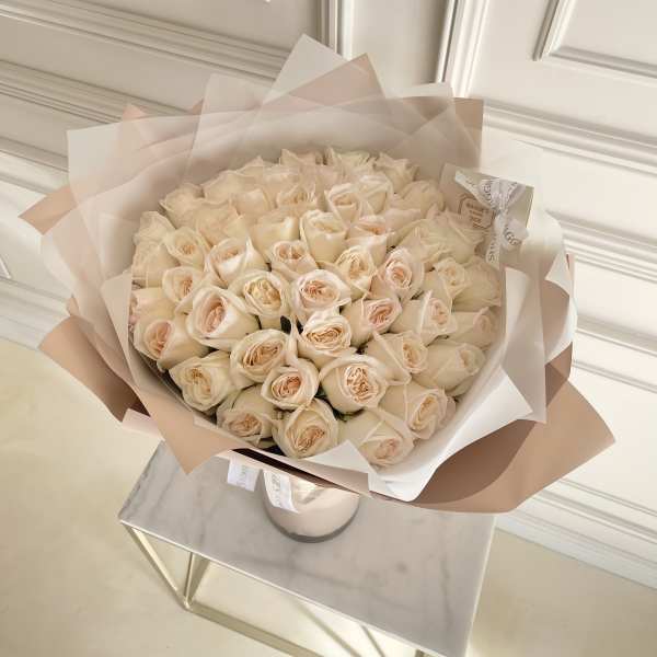 Bouquet of pale cream roses wrapped in blush paper