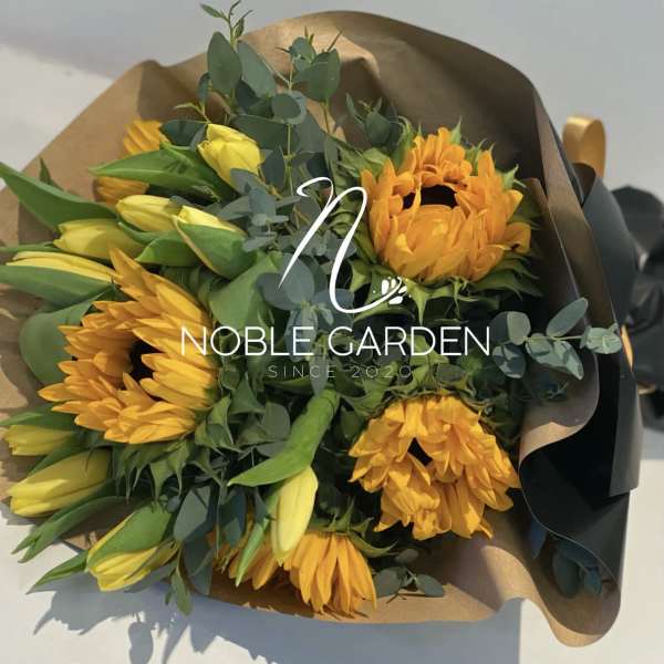 Bouquet of yellow tulips and orange sunflowers wrapped in brown paper